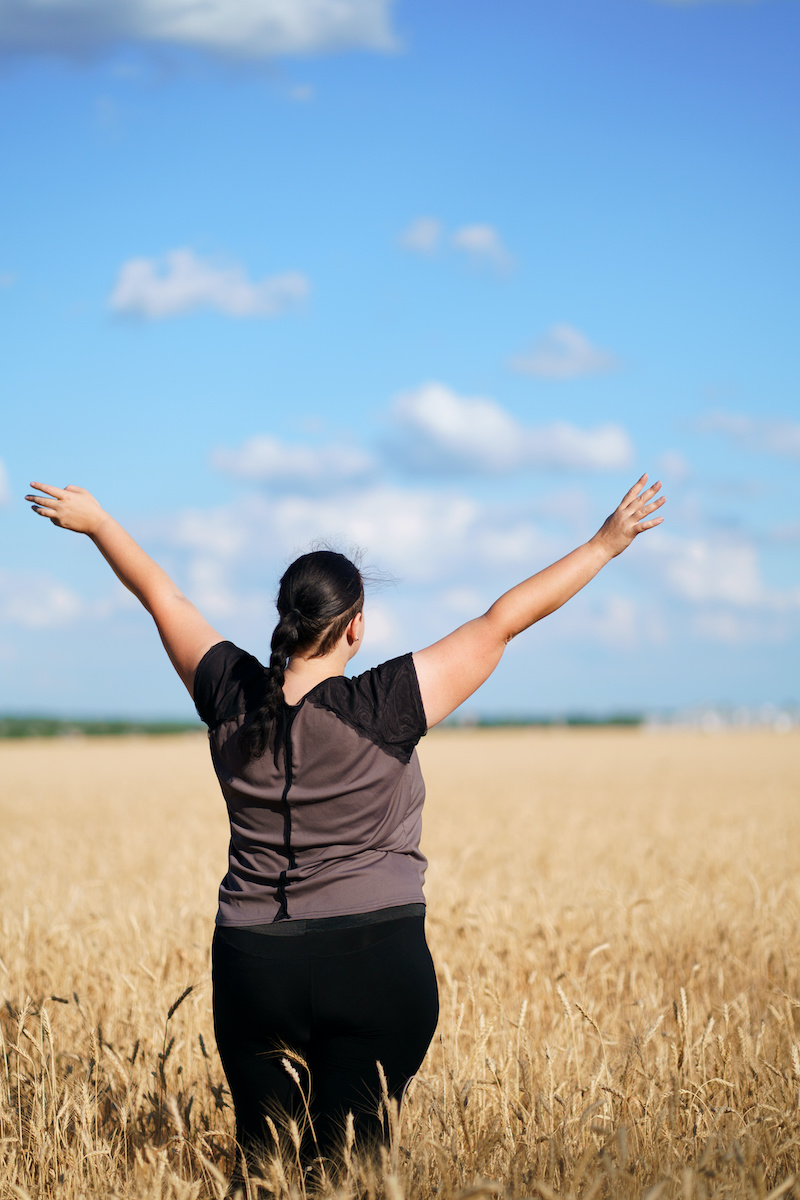 Overweight woman rising hands to the sky